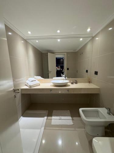 a bathroom with a sink and a toilet and a mirror at France Golf Apart - Flat Deluxe con estacionamiento privado, pileta y gimnasio in Río Cuarto
