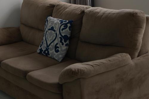 a brown couch with a blue and white pillow on it at Apartamento dalias em Holambra in Holambra