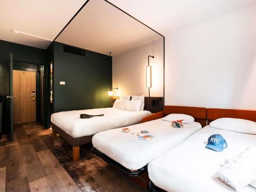 a hotel room with three beds and a mirror at Novotel Atria Nimes Centre in Nîmes
