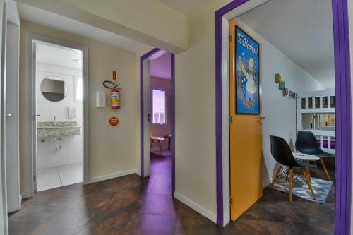 a hallway with a yellow door and a table and chairs at Hostel Toca da Moréia Bombinhas in Bombinhas