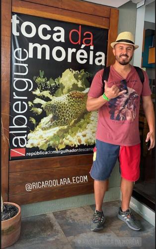 a man is standing in front of a sign at Hostel Toca da Moréia Bombinhas in Bombinhas
