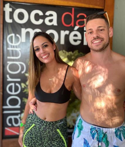 a man and a woman standing in front of a sign at Hostel Toca da Moréia Bombinhas in Bombinhas