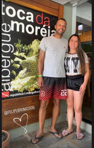 a man and a woman standing in front of a sign at Hostel Toca da Moréia Bombinhas in Bombinhas