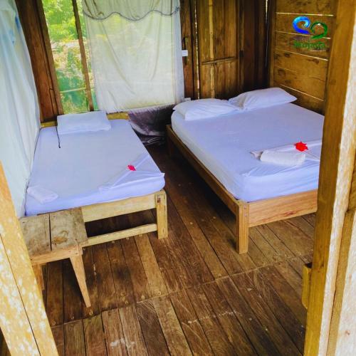 two twin beds in a room with wooden floors at Reserva Natural Selva Mojada in Nuquí