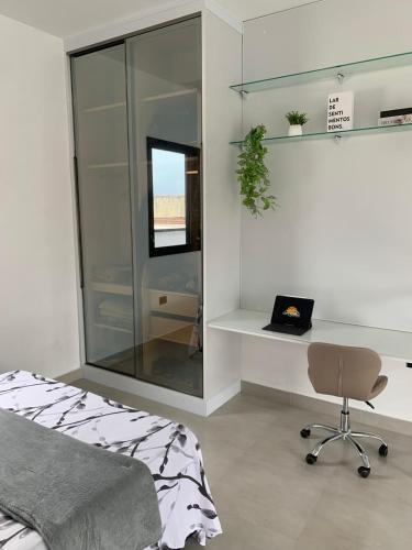 a bedroom with a bed and a desk and a chair at Loft de luxo em Peruíbe, 3 minutos da praia in Peruíbe