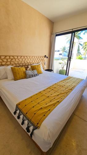 a large bed in a room with a large window at Casa Arrayan Telchac in Telchac Puerto