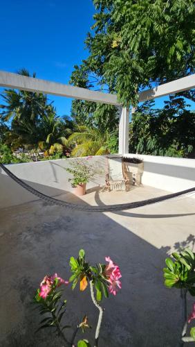 a hammock on a patio with flowers and a bench at Casa Arrayan Telchac in Telchac Puerto