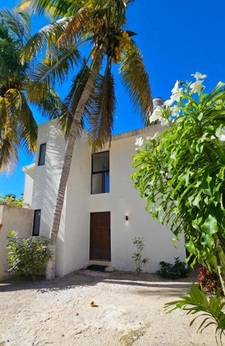 a white house with palm trees in front of it at Casa Arrayan Telchac in Telchac Puerto