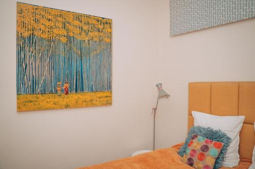a bedroom with a bed with a painting on the wall at ZevenVrijeDagen in Ghent