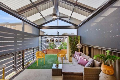a screened in porch with a couch on a balcony at Peaceful Retreat Steps from Semaphore Beach in Semaphore