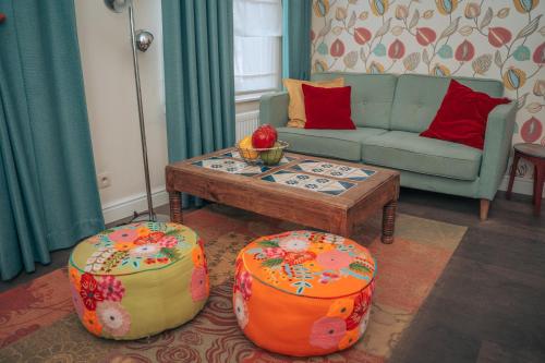 a living room with a couch and a table and two ottoman at ZevenVrijeDagen in Ghent