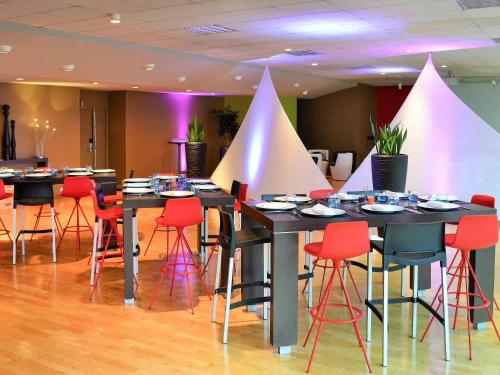 a dining room with tables and red chairs at Mercure Besancon Parc Micaud - Hotel & Bar in Besançon