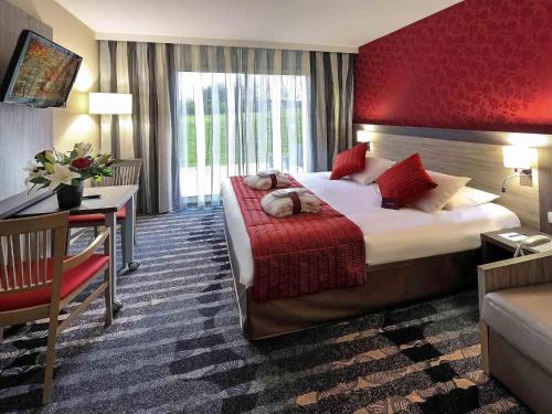 a hotel room with a large bed and a desk at Mercure Rouen Val de Reuil in Val de Reuil