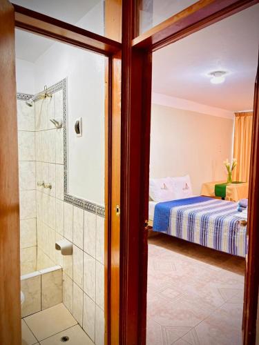 a bedroom with a bed and a shower and a bathroom at Hospedaje Carrasco Cajamarca in Cajamarca