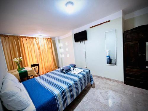 ein Schlafzimmer mit einem Bett mit einer blau-weißen Decke in der Unterkunft Hospedaje Carrasco Cajamarca in Cajamarca