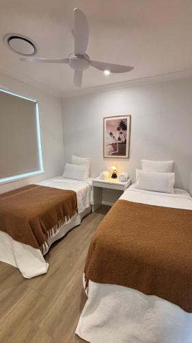 a room with two beds and a ceiling fan at Entire Unit 02 Rooms 04 King Single Beds 11 kms to Goldcoast Airport in Terranora