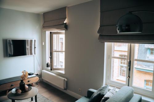 a living room with a couch and two windows at ZevenVrijeDagen in Ghent