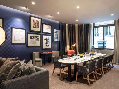 a dining room with a table and chairs and a couch at Sofitel Paris Arc De Triomphe in Paris