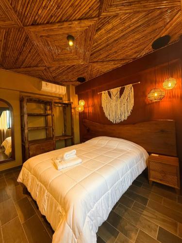 a bedroom with a large white bed with wooden ceilings at Hotel Quincha y Adobe in Huanchaco