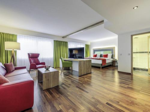 a living room with a couch and a table at Mercure Hotel Saarbrücken City in Saarbrücken