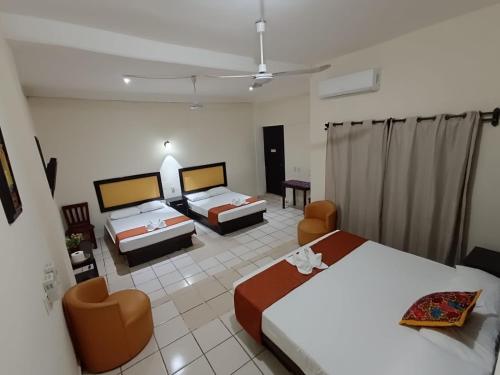 a hotel room with two beds and two chairs at Hotel Rio Maya in Palenque
