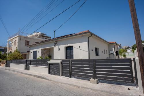 a white house with a black fence on a street at Raise Cityscape Limassol Suites in Limassol