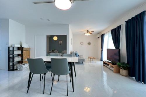 a white living room with a table and chairs at パイナガマリゾート AZAMi-8 in Miyako-jima