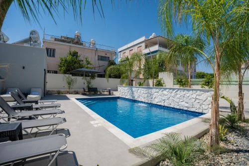 a swimming pool with chairs and a building at Raise Cityscape Limassol Suites in Limassol