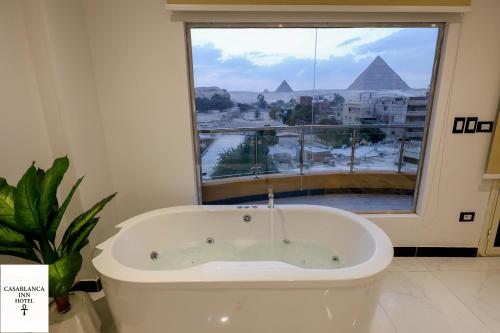 a bath tub in a bathroom with a view of the pyramids at Casablanca pyramids inn in Cairo