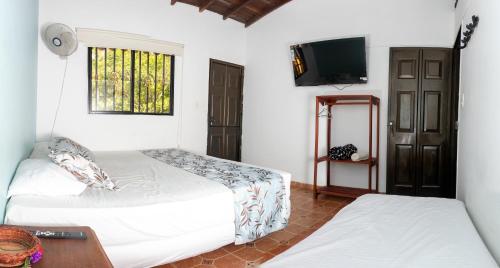 a bedroom with two beds and a television in it at Hotel Quinta del Muelle Campestre in San Gil