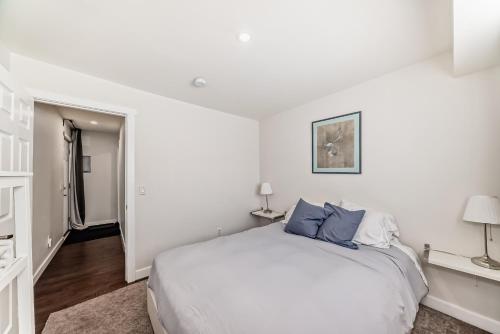 a white bedroom with a bed and two lamps at Laneway Carriage House in Calgary