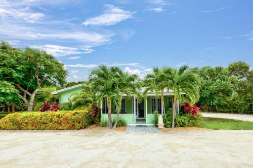 a green house with palm trees in front of it at Private Cottage on Bayfront Estate with Pool, Beach, Dockage, Kayaks and More in Islamorada