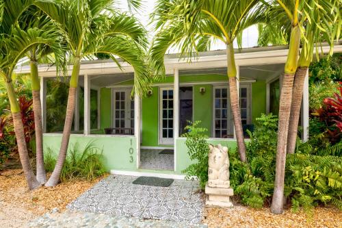 a green house with palm trees in front of it at Private Cottage on Bayfront Estate with Pool, Beach, Dockage, Kayaks and More in Islamorada