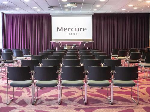 a room filled with chairs in front of a screen at Mercure Tours Nord in Tours