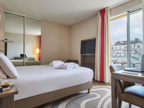 Una habitación de hotel con una cama, un escritorio y un televisor. en Mercure Tour Eiffel Grenelle, en París