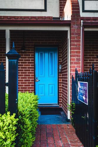 a blue door on a brick house with a fence at Barkers Run Terrace in Castlemaine