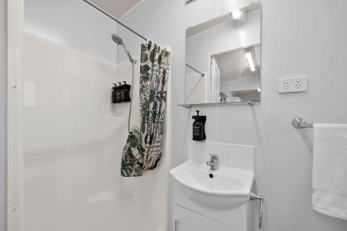 a white bathroom with a sink and a mirror at Shepparton Holiday Park and Village in Shepparton