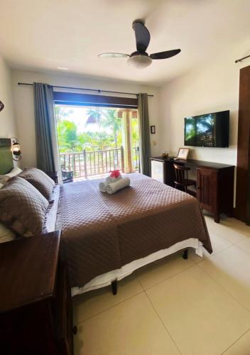 a bedroom with a bed and a desk and a window at Pousada Chantilly in São Miguel do Gostoso