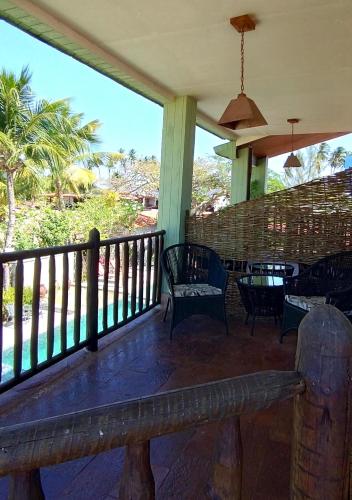 a porch with a bench and a table and chairs at Pousada Chantilly in São Miguel do Gostoso