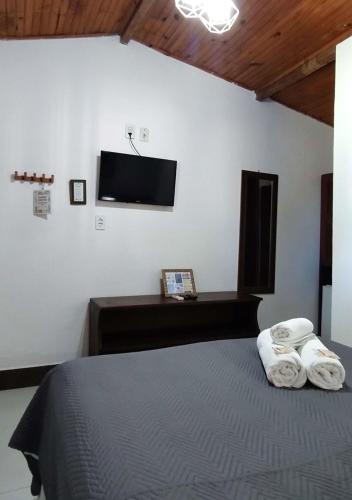 a bedroom with a bed and a flat screen tv at Pousada Chantilly in São Miguel do Gostoso