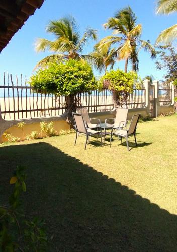 a table and chairs in a yard with palm trees at Pousada Chantilly in São Miguel do Gostoso