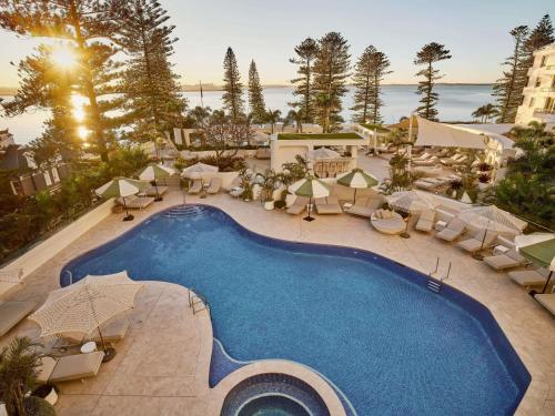 an overhead view of a swimming pool with chairs and umbrellas at The Brighton Hotel Sydney - Mgallery Collection in Sydney