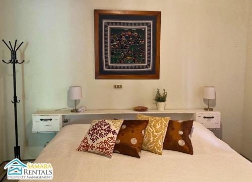 1 dormitorio con 1 cama con almohadas y una foto en la pared en Cozy Apartment Downtown, en Nicoya