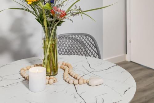 a white marble table with a vase of flowers and a candle at Gateway Suites Near Canmore and Banff in Canmore