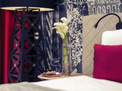a vase with flowers on a table with a plate of food at Mercure Budapest Castle Hill in Budapest