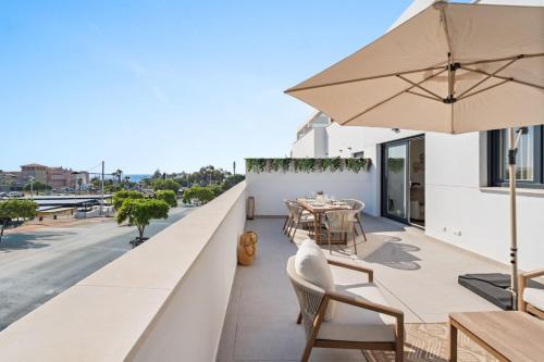Un balcón con una mesa y sillas y una sombrilla. en Sea View Apartment Estepona - Célere Sea Views, en Estepona