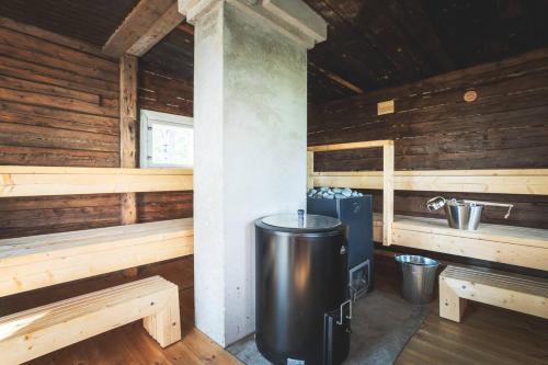 Un interior de una cabaña de madera con bancos y una estufa. en Stay North - Honkala, en Ruissalo