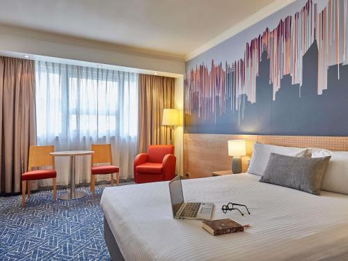 Una habitación de hotel con una cama y una computadora portátil encima. en Mercure Perth, en Perth