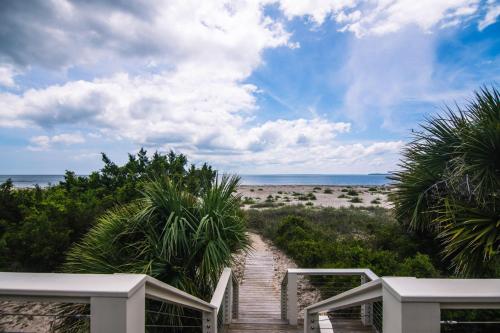 a wooden walkway to the beach with palm trees at Crowfield in Edisto Beach