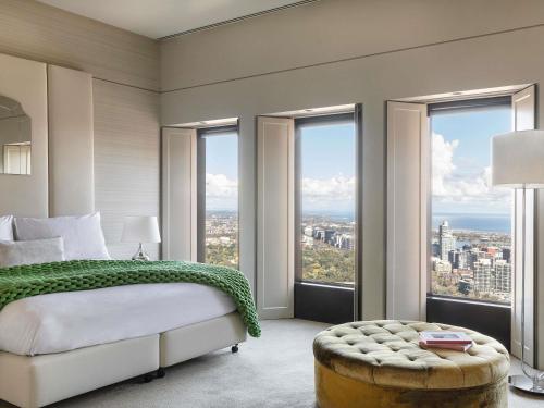 a bedroom with a bed and windows with a view at Sofitel Melbourne On Collins in Melbourne